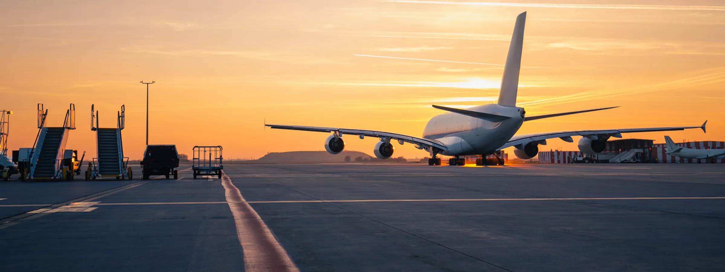 Groot passagiersvliegtuig op de startbaan van Naxos luchthaven bij zonsondergang met boardingtrappen naast het vliegtuig.
