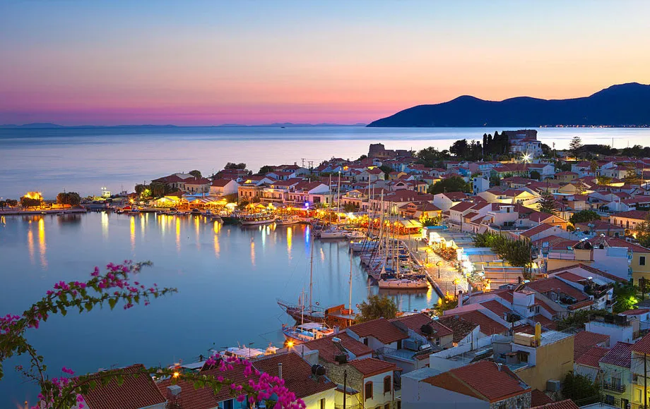 Porto di Samos al tramonto con barche ormeggiate, case tradizionali e mare calmo sull’isola greca.