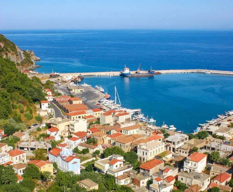 Port animé de Karlovasi à Samos, avec bateaux, eaux bleues et maisons aux toits rouges entourées de collines verdoyantes.