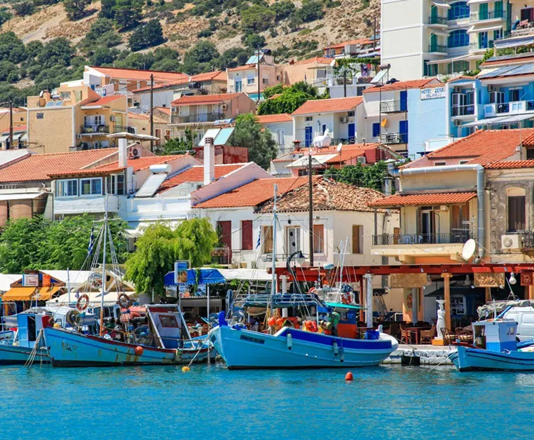 Porto di Pythagorion a Samos con barche da pesca colorate e case tipiche con tetti arancioni sullo sfondo.