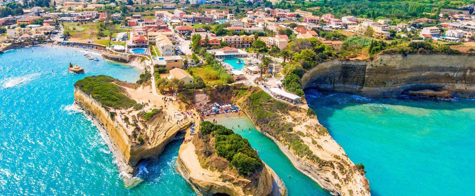 Corfu coastline with cliffs, turquoise sea, beaches and resort buildings near the water for car rental.