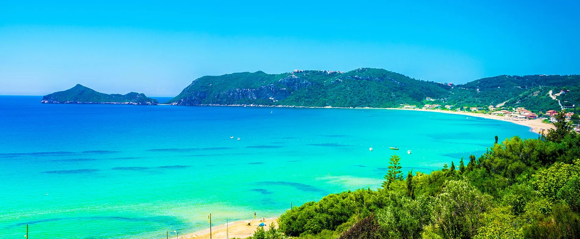 Blue sea and golden beach at Corfu island with green hills and boats near the shore for a relaxing holiday.