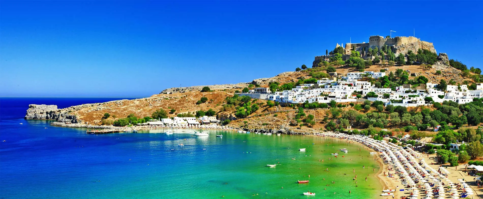 Plage de Lindos et acropole antique sur l'île de Rhodes avec mer turquoise et baigneurs, parfait pour location de voiture.