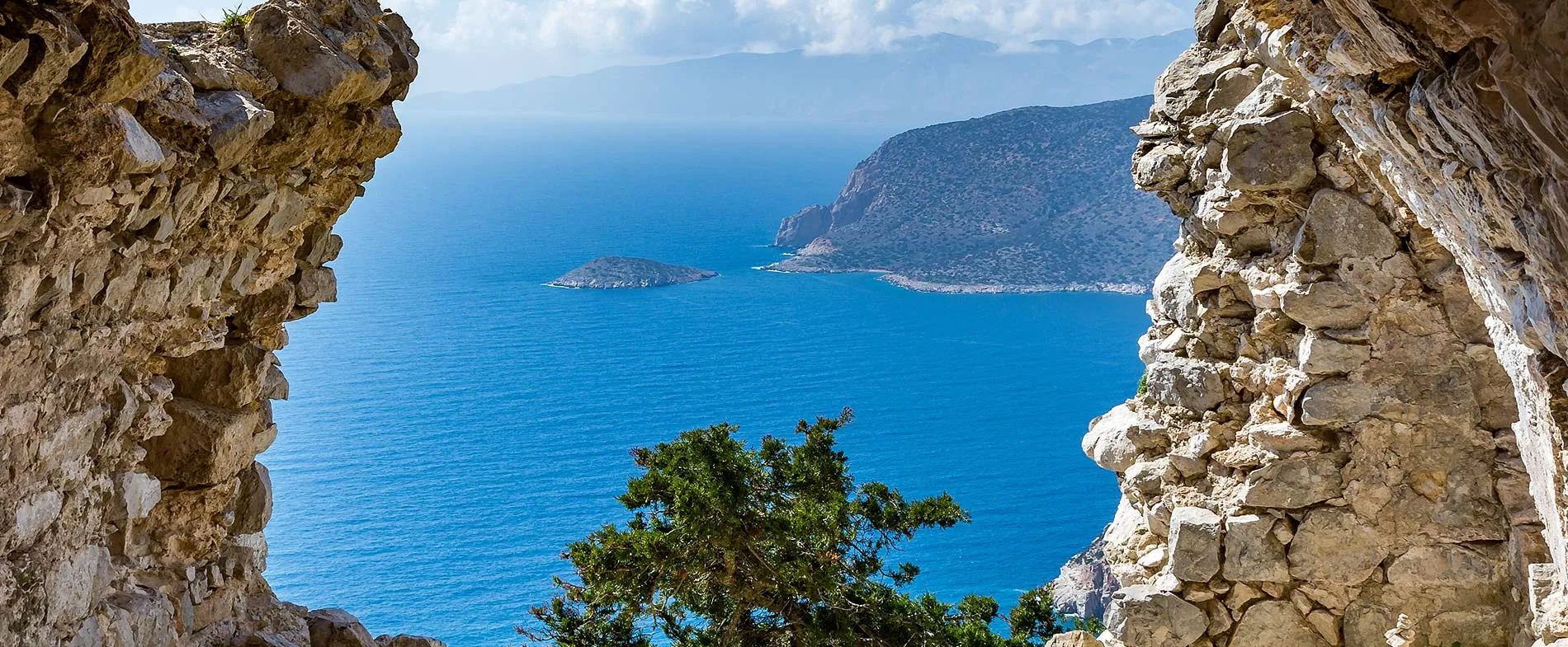 Blick auf das Mittelmeer und felsige Küste eingerahmt von antiken Steinruinen auf Kreta.