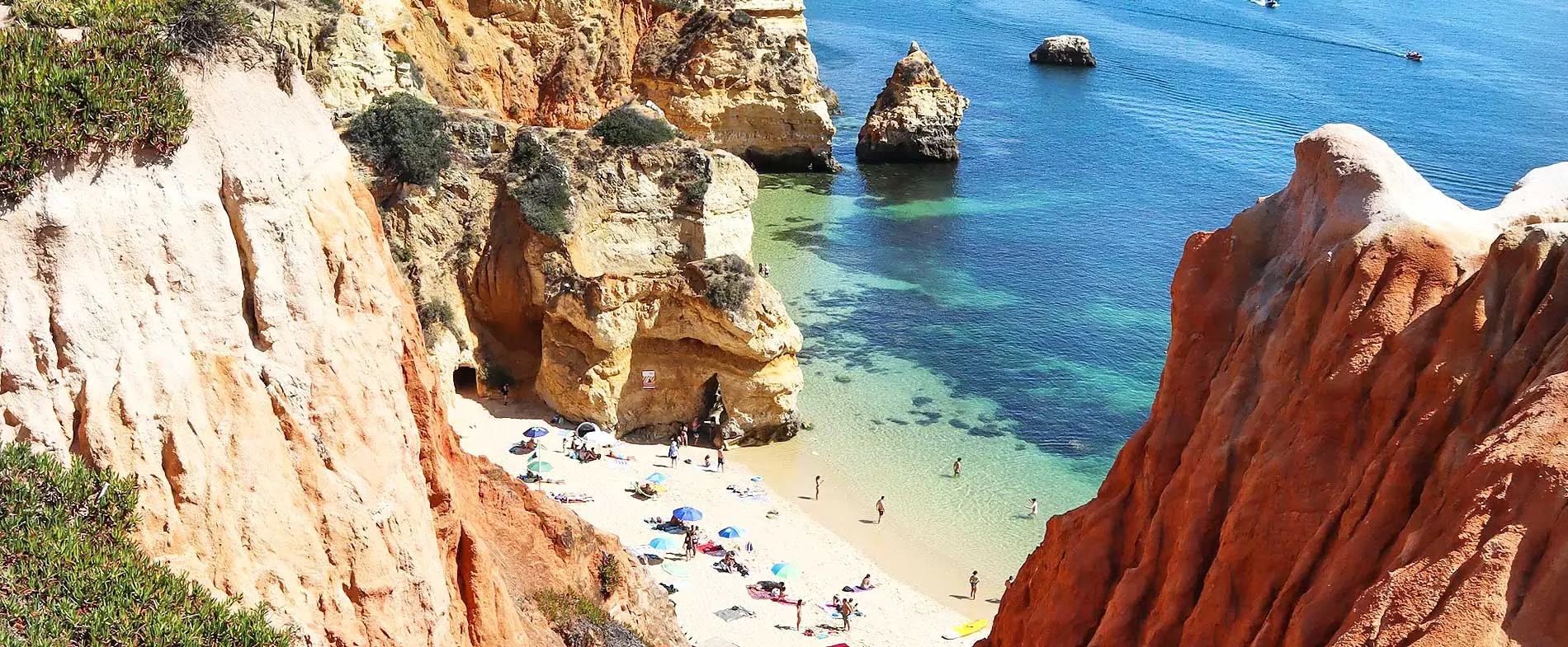 Lagos beach with turquoise waters and sandy shore surrounded by rocky cliffs in Algarve, Portugal.