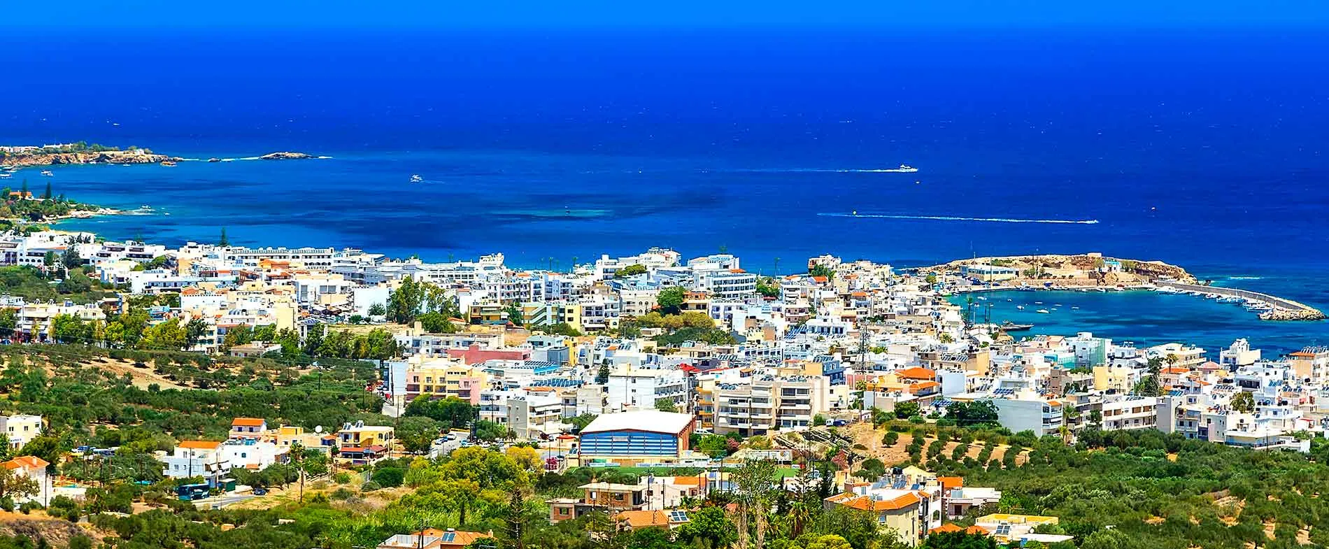 Ville d'Agios Nikolaos sur l'île de Crète avec la mer, des bateaux et des bâtiments côtiers.