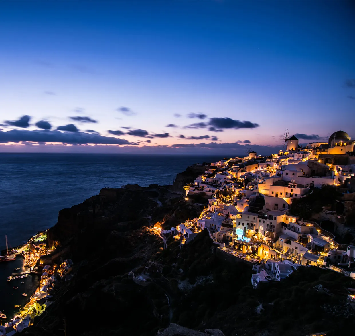 Santorini town lit up at twilight overlooking the sea, perfect for car rental adventures in Greece.
