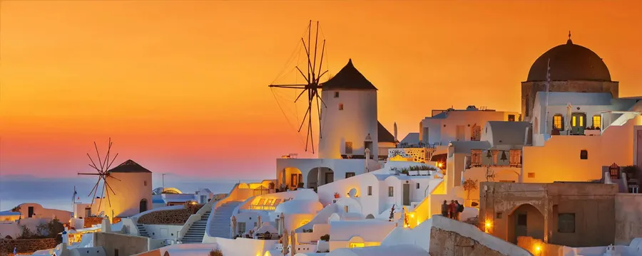 Santorini sunset over white buildings and windmills in Greece, perfect for car rental vacations.