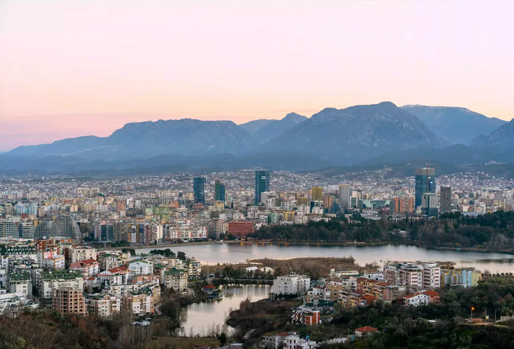 Tirana city skyline with lakes and mountains in the background, a popular travel destination for car rental.