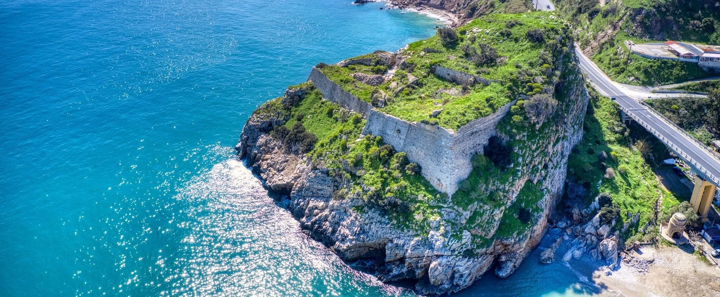Luftaufnahme der Festung Palamidi auf einer felsigen Halbinsel mit grüner Vegetation am blauen Meer.