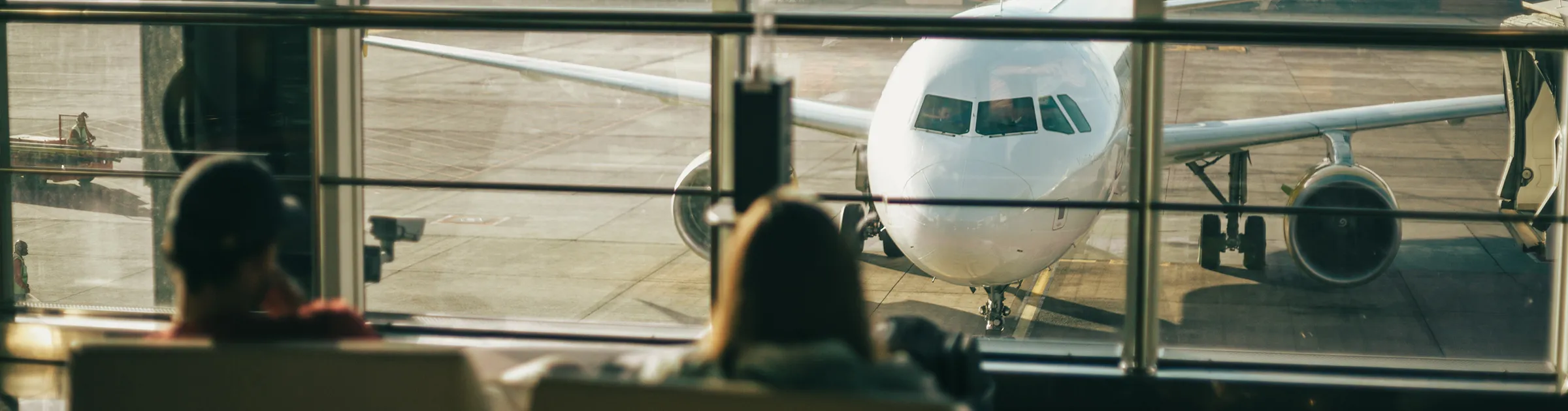 Airport terminal with passengers waiting near a plane parked at the gate for car rental customers.