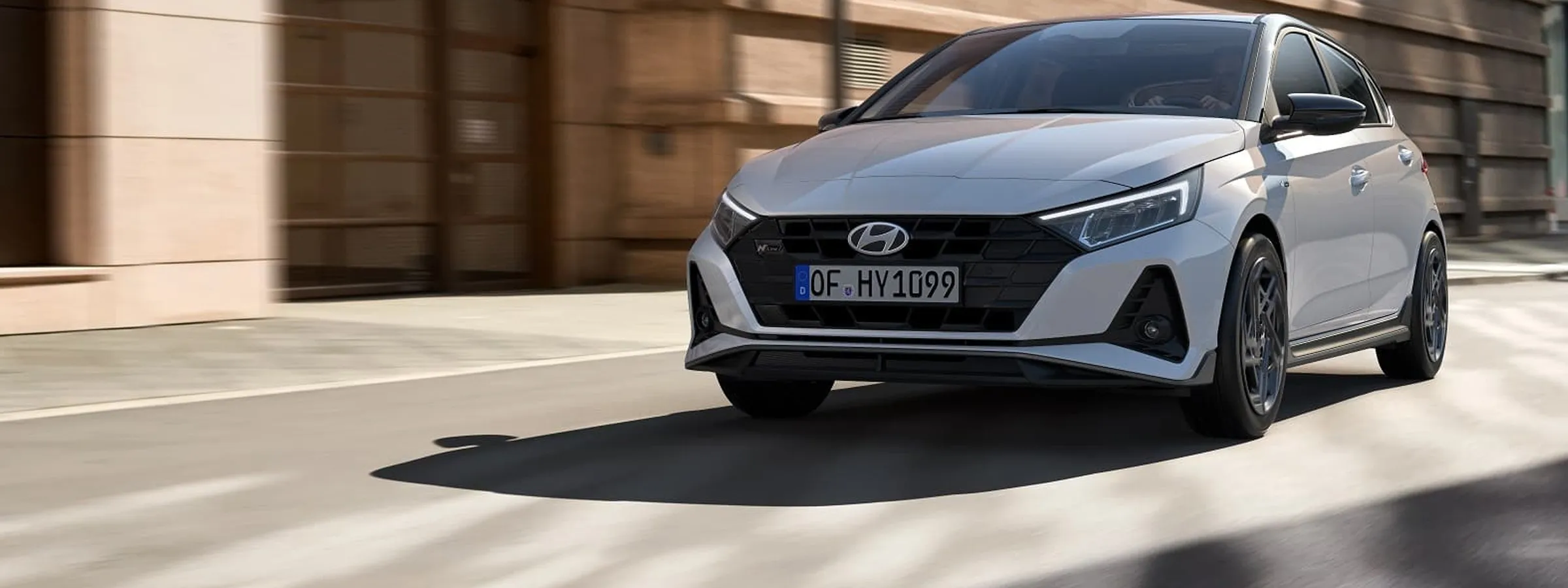 Hyundai hatchback mașină de închiriat care circulă pe o stradă urbană în lumina puternică a zilei.