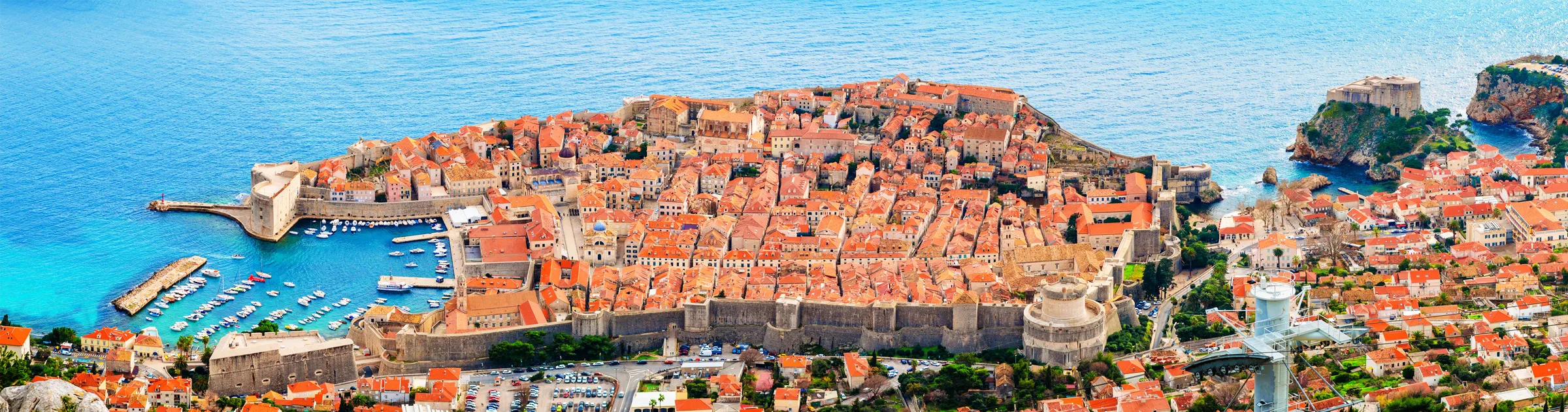 Dubrovnik old town fortified city surrounded by sea and red rooftops, popular car rental destination.