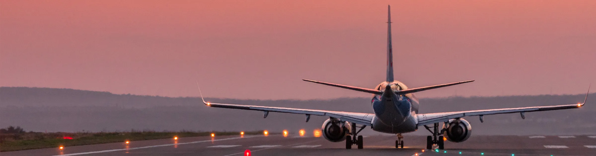 Airplane taxiing on runway at sunset, airport scene for travel and car rental connections.