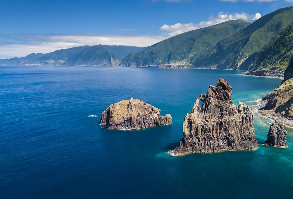 Costa da Madeira com formações rochosas impressionantes emergindo do profundo oceano Atlântico.
