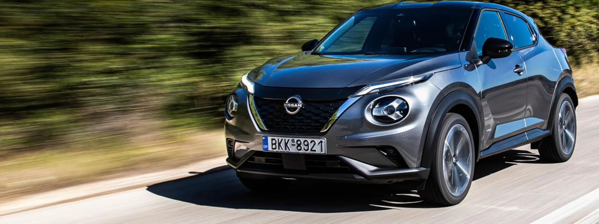 Nissan Juke carro de aluguer a circular numa estrada com fundo verde desfocado para aluguer.