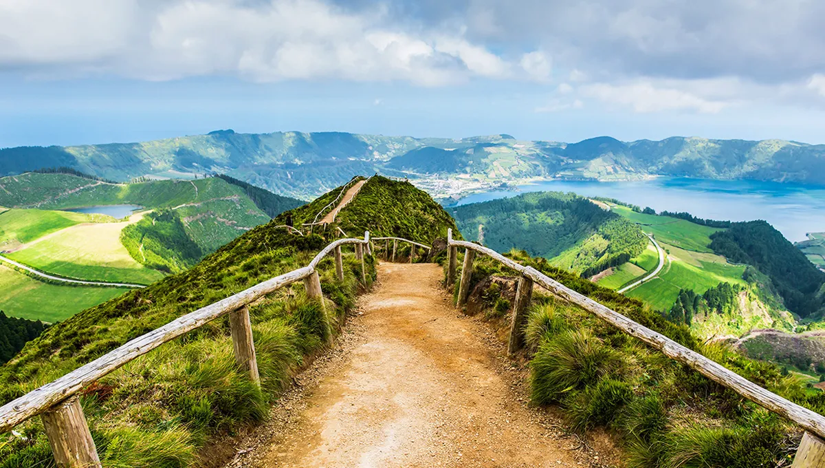 Scenic hiking trail overlooking green hills and lakes in the Azores, ideal for car rental road trips.