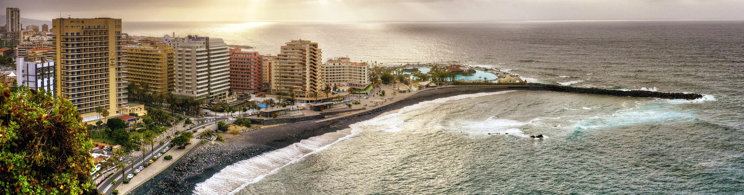 Scorcio costiero con spiagge e hotel urbani al tramonto per destinazione noleggio auto.