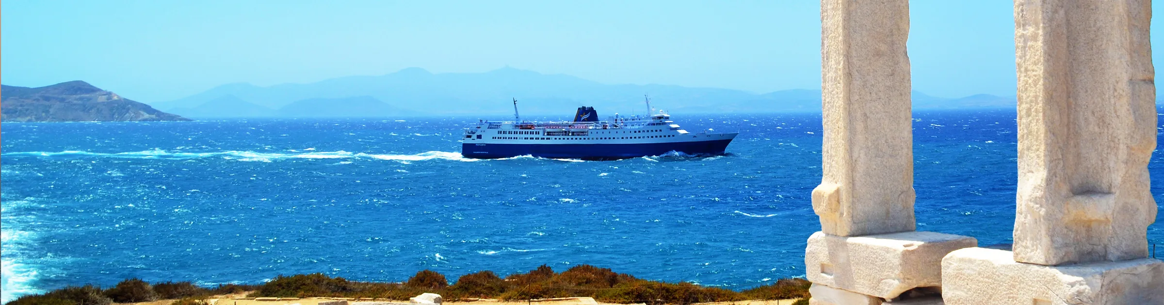 Fährschiff fährt in der Nähe der Insel Naxos mit antiken griechischen Ruinen und blauem Meer.