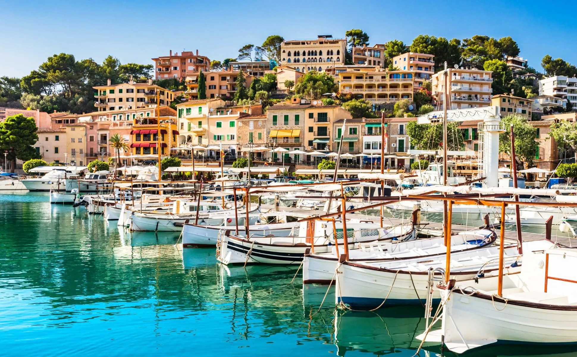Port de Sóller harbor with boats and colorful buildings on a sunny day.