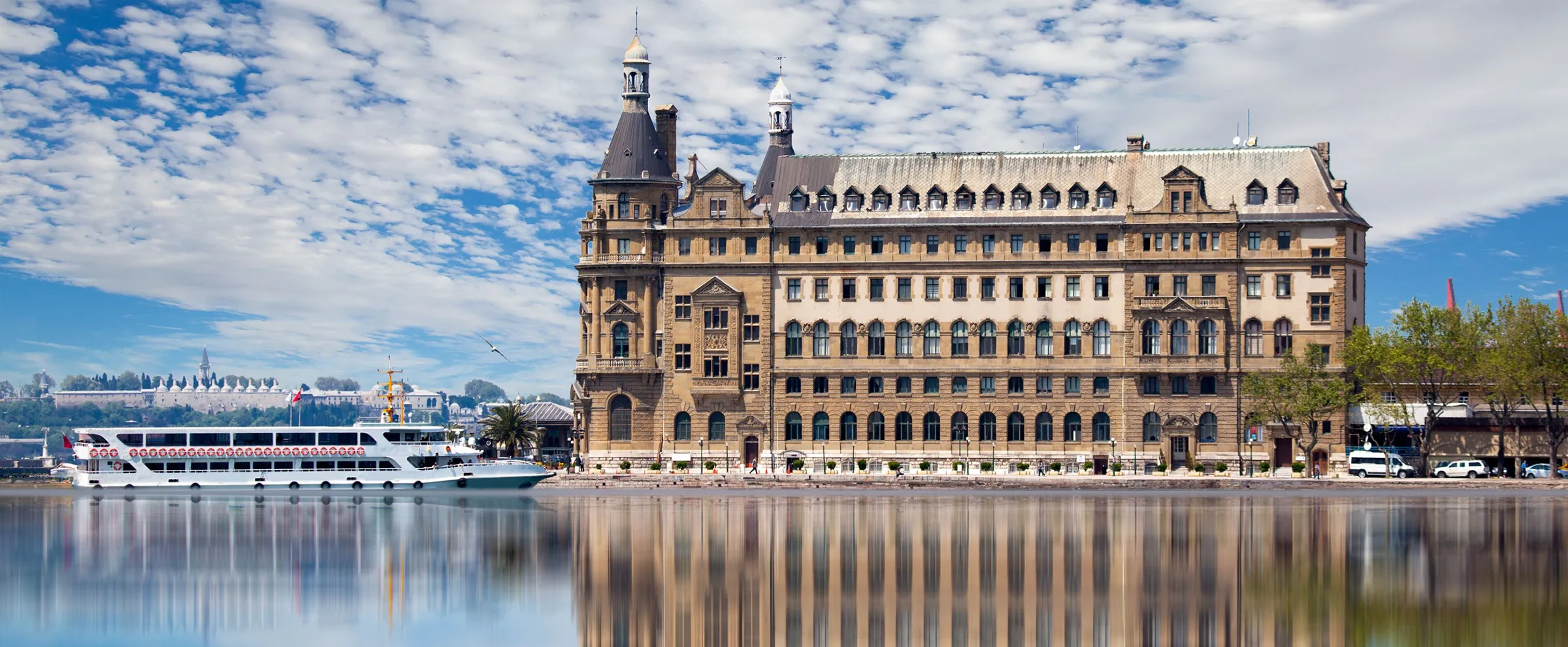 Haydarpaşa tren istasyonu, İstanbul'da kısmen bulutlu gökyüzü altında su kenarında.