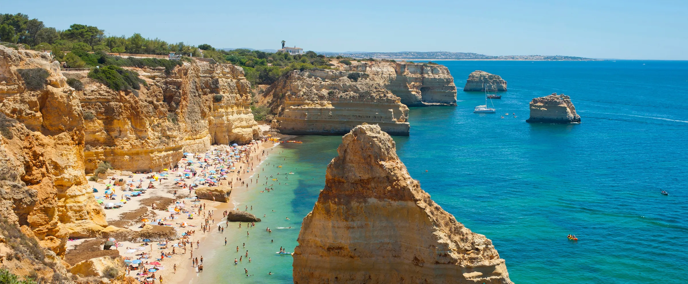 Lagos Algarve beach with cliffs and people enjoying the sunny day by the sea.