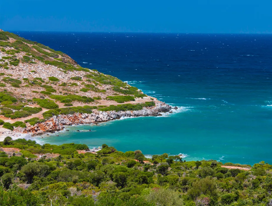 Coastal scenery with a rocky hill and turquoise sea, perfect for a relaxing car rental road trip.
