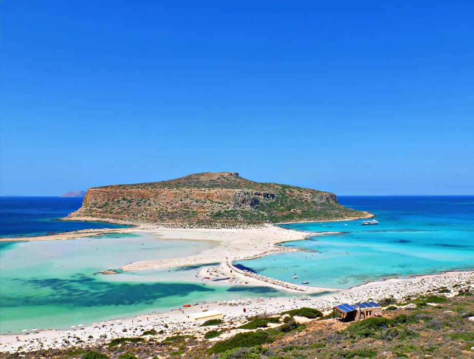 Balos Beach in Crete with turquoise waters and sandy peninsula surrounded by rocky hills and clear skies.
