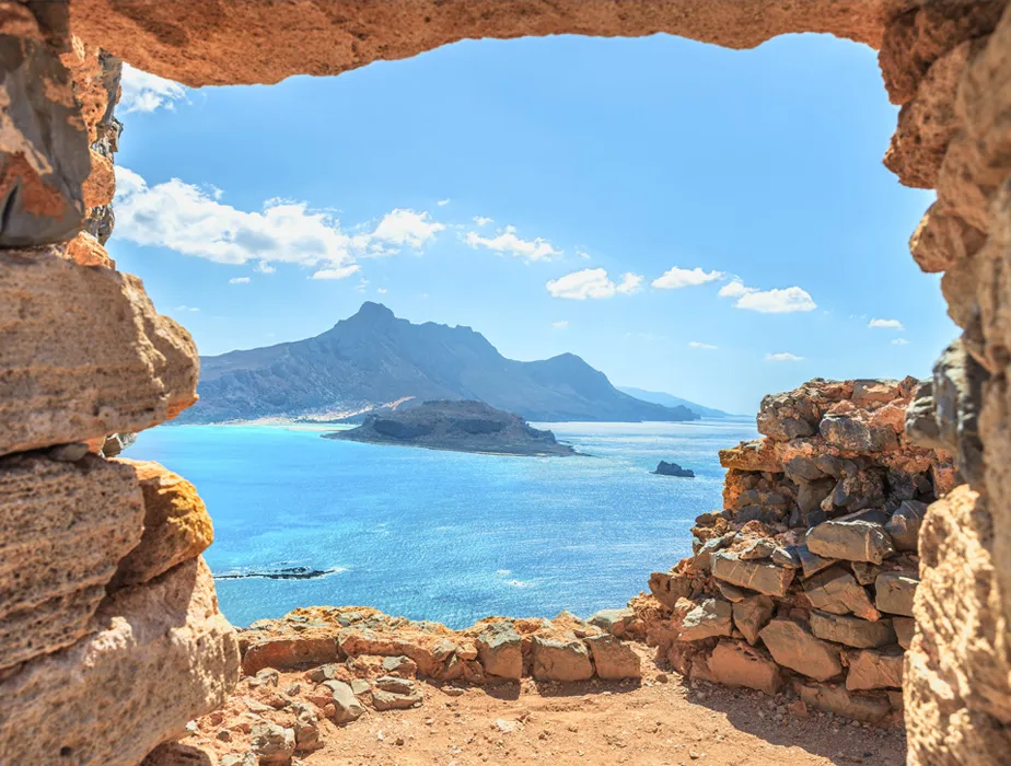 View of Balos Lagoon in Crete, Greece, seen through an ancient stone window opening.