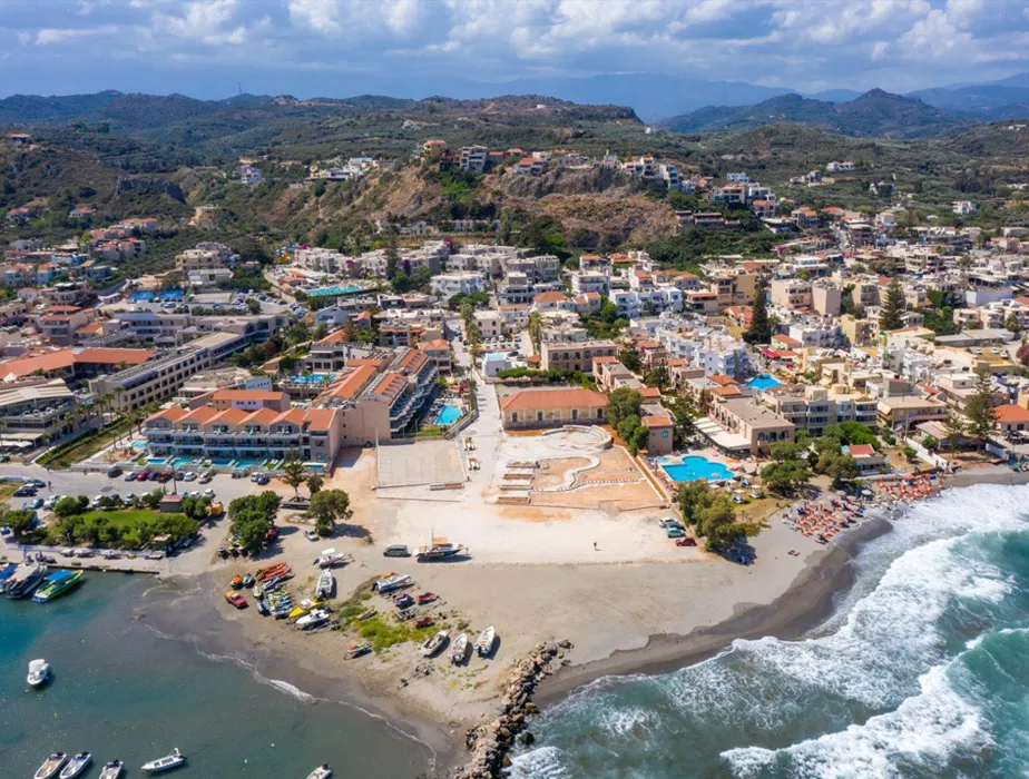 Agios Nikolaos coastal town in Crete with sandy beaches, boats, and hillside buildings.
