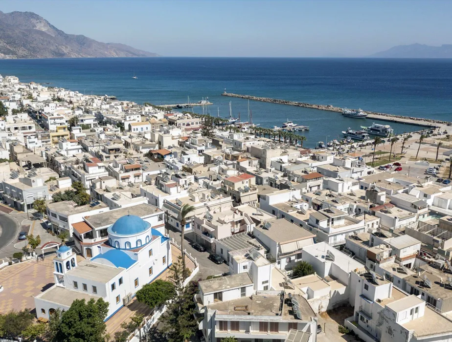 Naxos town harbor with white buildings and blue-domed church by the sea, perfect for car rental trips.