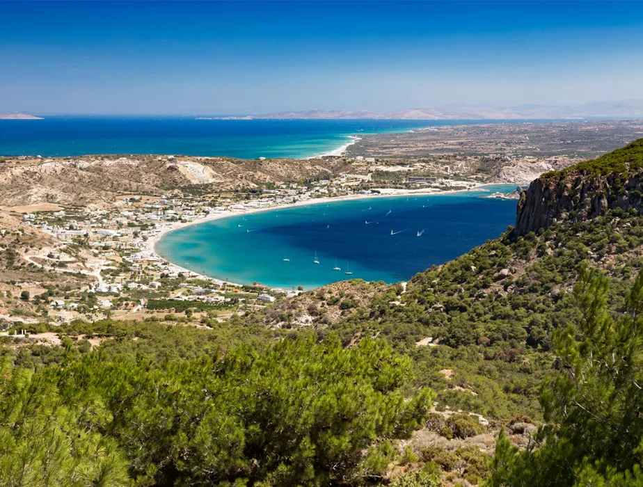 Livadia Bay in Kos with its blue waters and surrounding green hills, popular for boat rental activities.