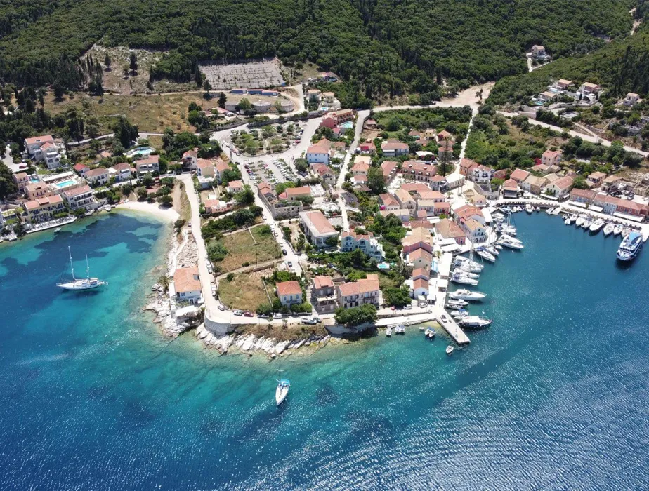 Small coastal village with boats docked at the marina and clear turquoise sea along the shoreline.