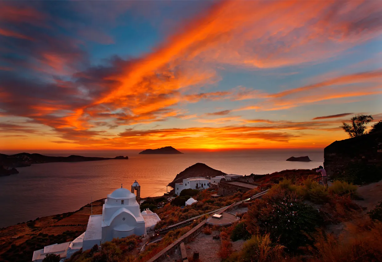 Santorini sunset with white chapel and sea view, ideal for car rental trips in Greece.