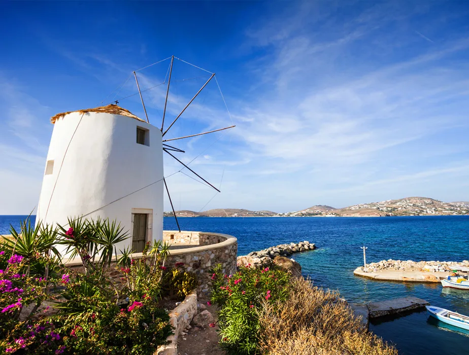 Mykonos windmill by the sea with bright flowers and clear blue sky under sunny weather.