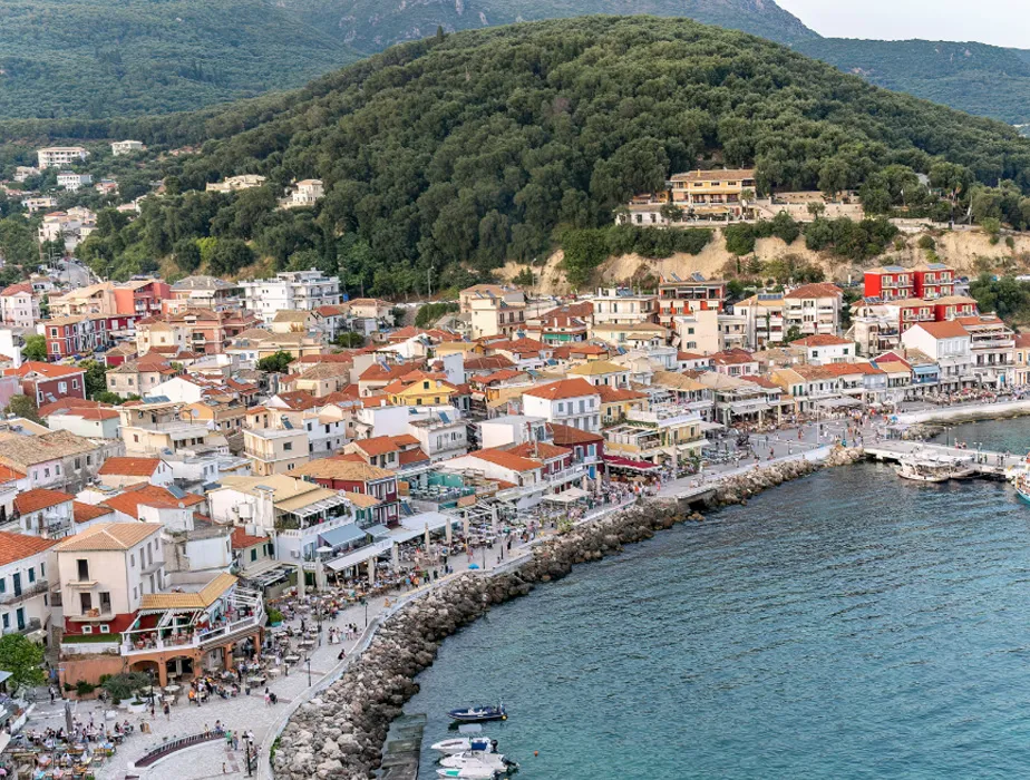 Parga coastal town with colorful buildings by the sea and green hills in the background.