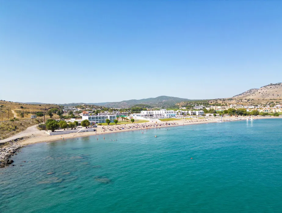 Beach resort in a coastal town with clear blue water and sunbathers along the sandy shore.