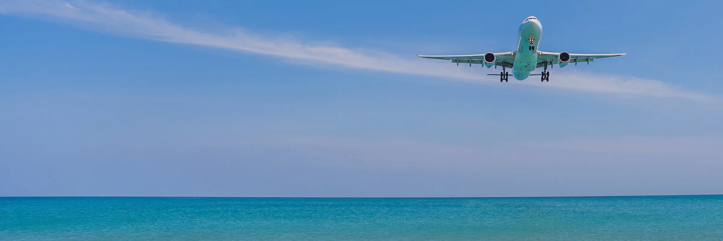 Aereo in fase di atterraggio sopra il mare blu e il cielo limpido.