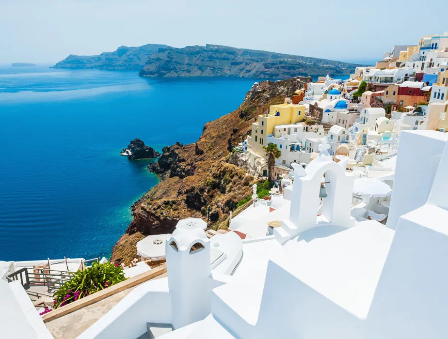 Santorini coastline with white buildings and blue sea in a popular Greek rental car destination.