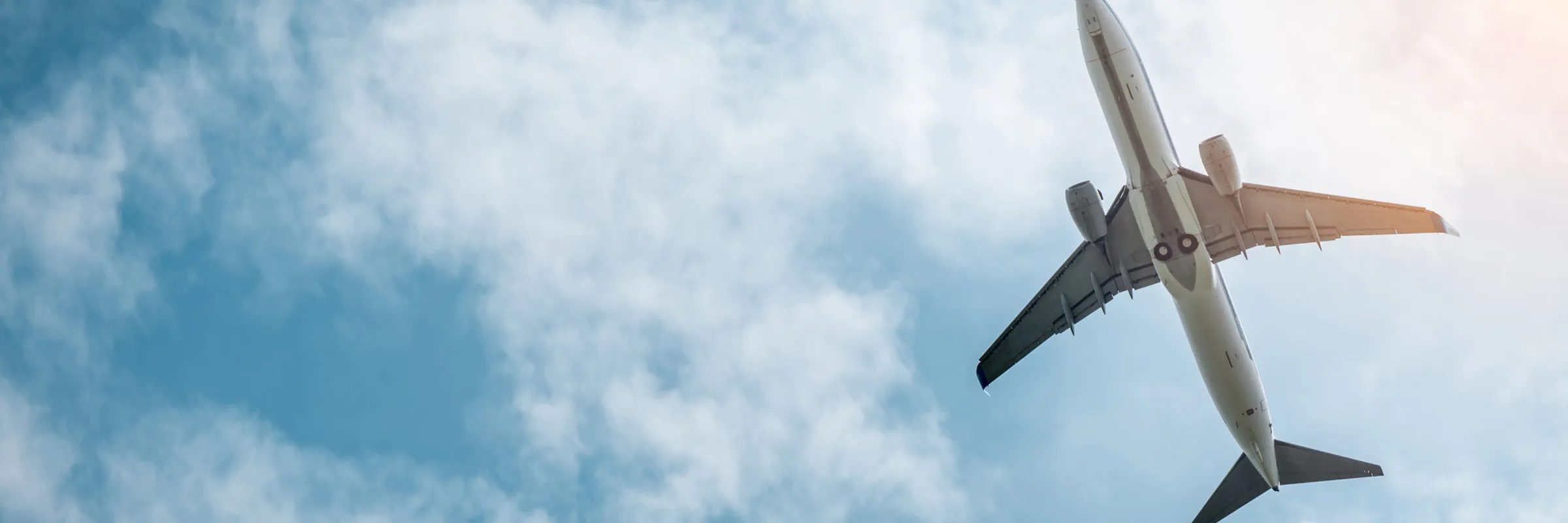Handelsflugzeug fliegt in einem teilweise bewölkten blauen Himmel und symbolisiert Reise- und Flughafendienste.