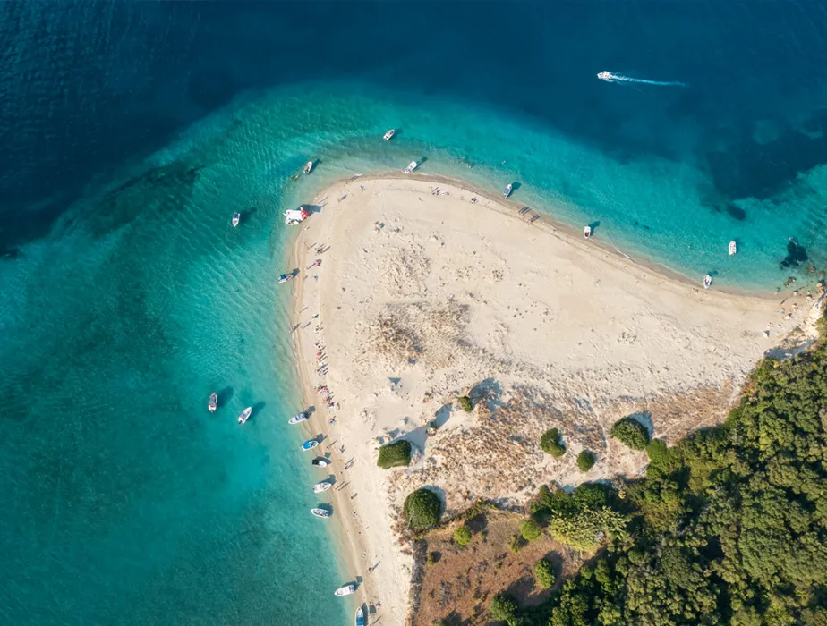 Sarakiniko Beach in Zakynthos with boats near the sandy shore and clear blue sea water.