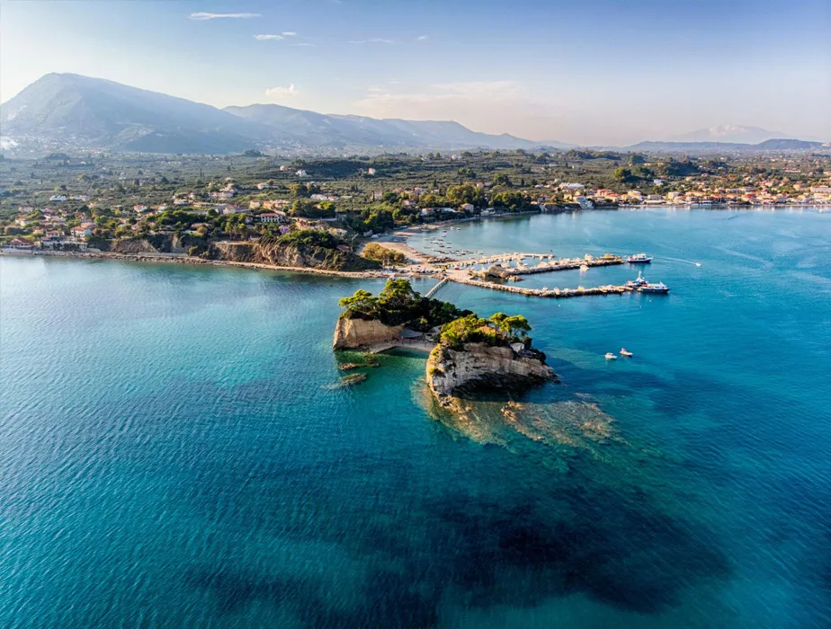 Zante coastal view with small islets, clear blue sea, and mountain landscape in the background.