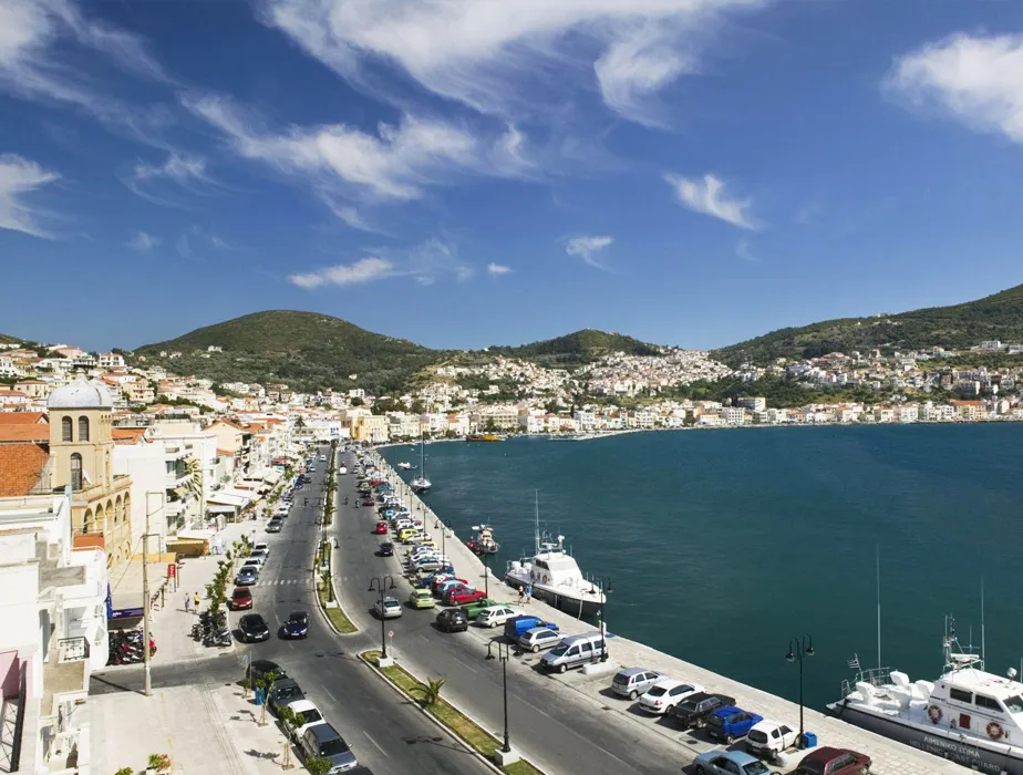 Pylos sahil kasabası, liman yolunda park etmiş arabalar ve suda teknelerle.