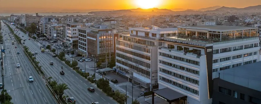 Athens city skyline with a busy road and sunset, showing urban buildings and traffic flow for car rental.