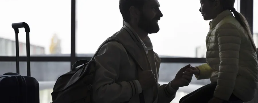 Άντρας και παιδί σε αεροδρόμιο με αποσκευές, ιδανικό σκηνικό για υπηρεσίες ενοικίασης αυτοκινήτων.