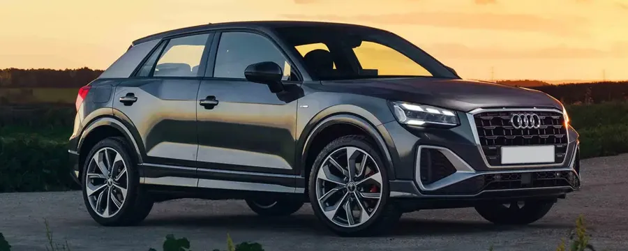 Audi Q2 compact SUV available for rent, shown parked at sunset on a country road.