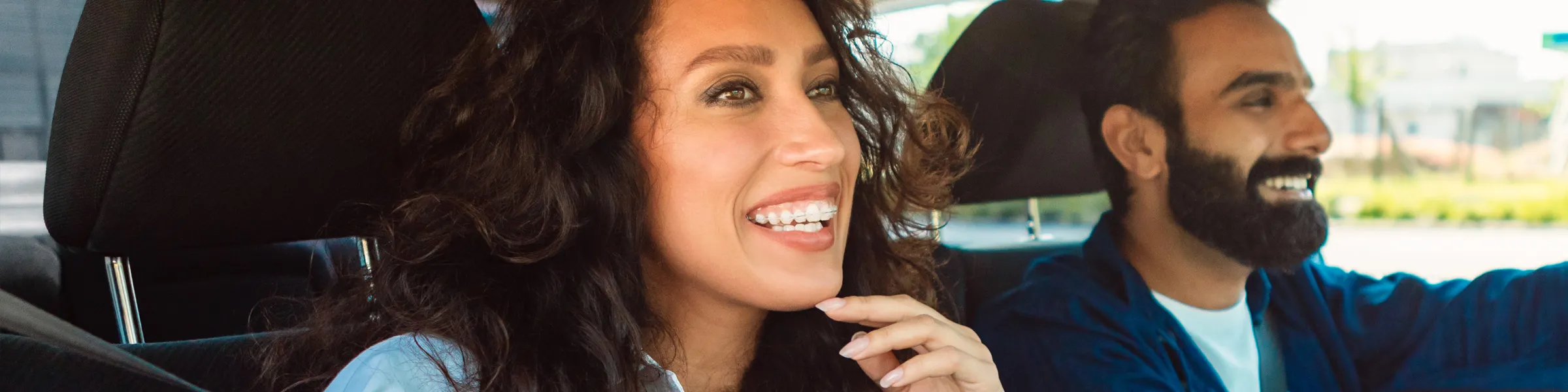 Gelukkige vrouw met beugel en man die lacht terwijl ze samen in een auto rijden.