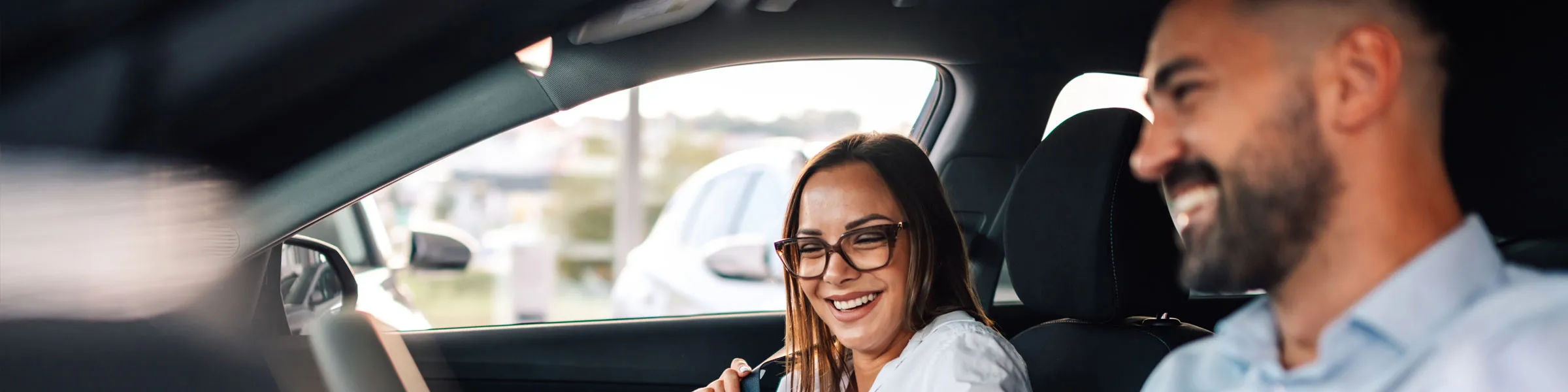 Couple smiling inside a rental car, enjoying a pleasant moment during car hire.
